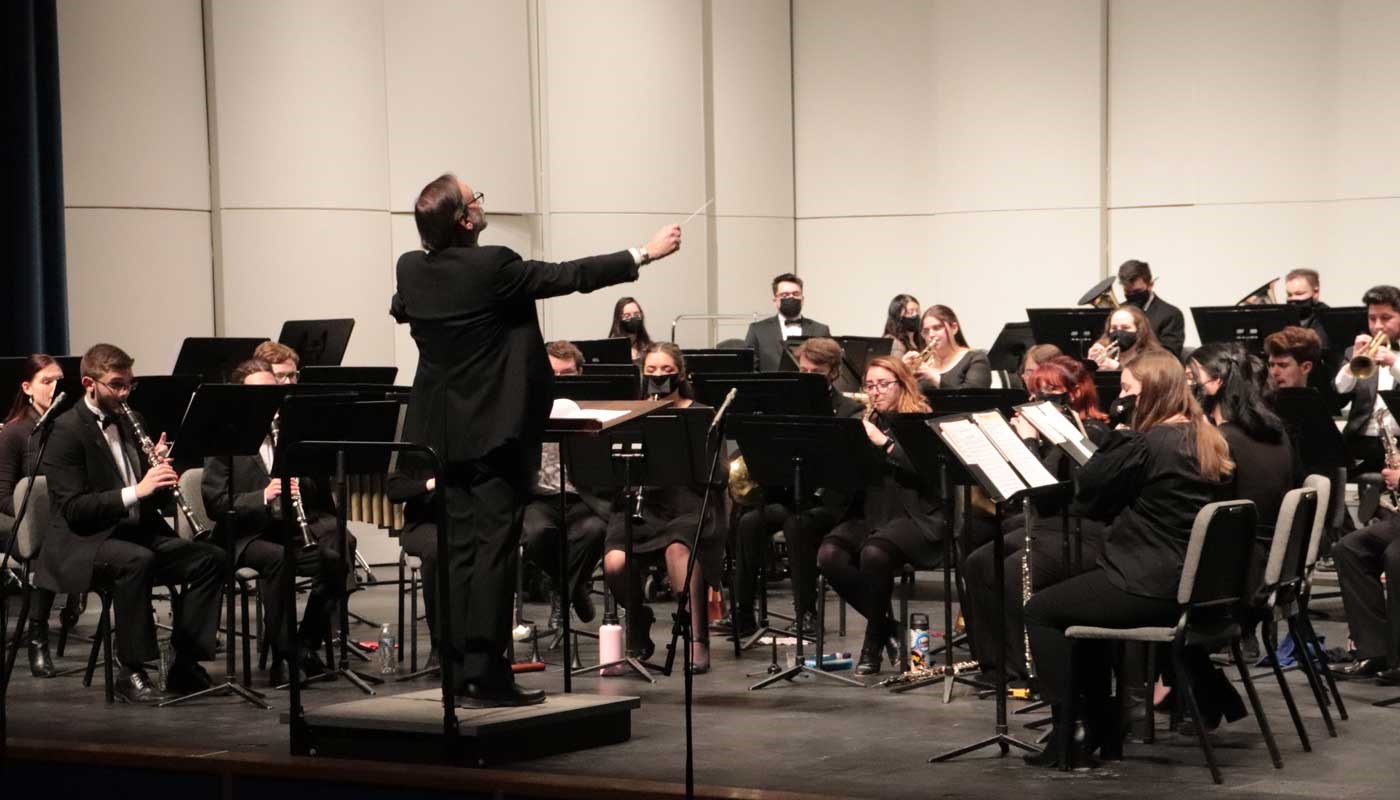 Conductor directs the UMass Lowell Wind Ensemble on a stage