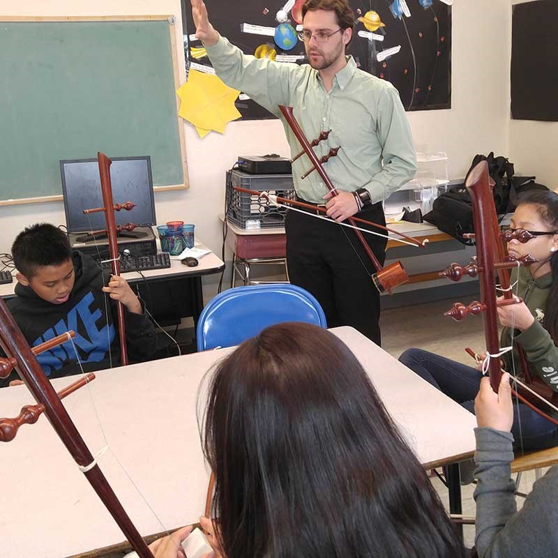 A music teacher in the classroom teaching young students with instruments.