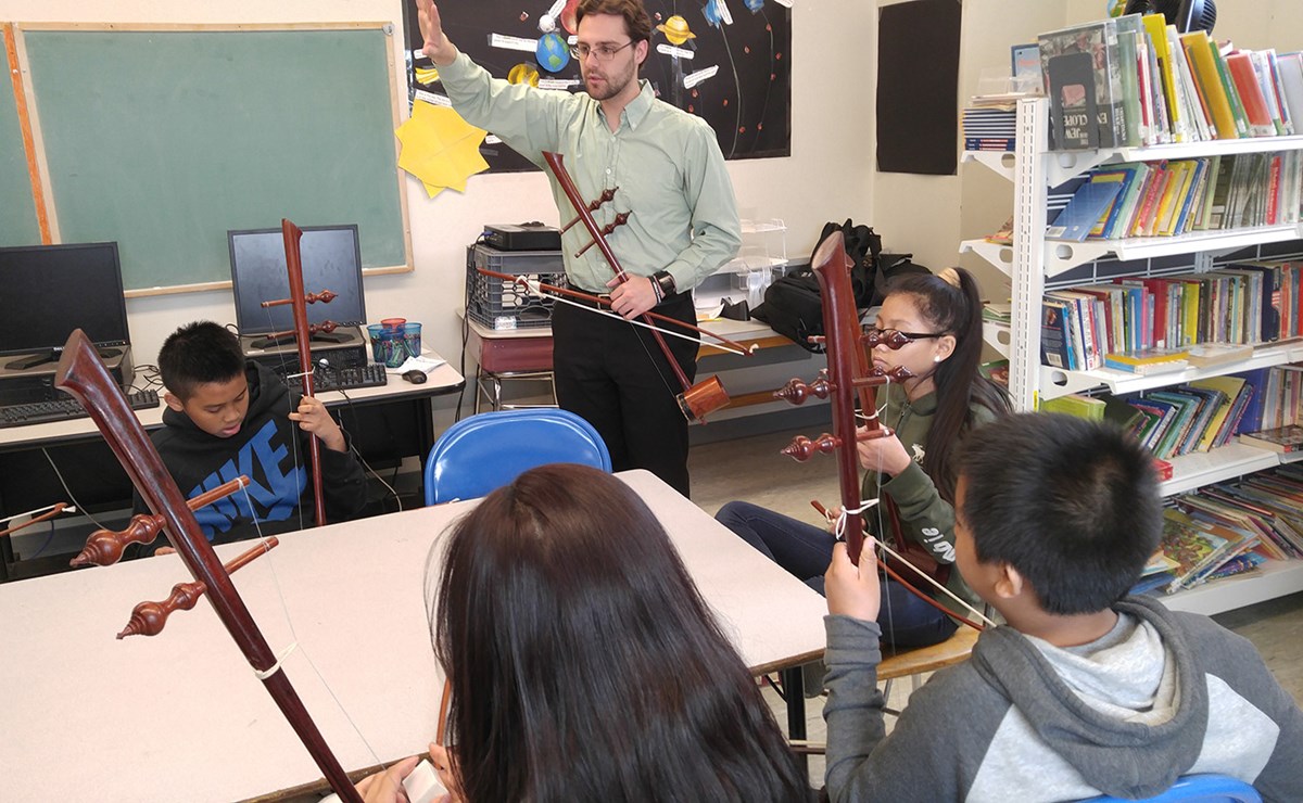 A music teacher in the classroom teaching young students with instruments.