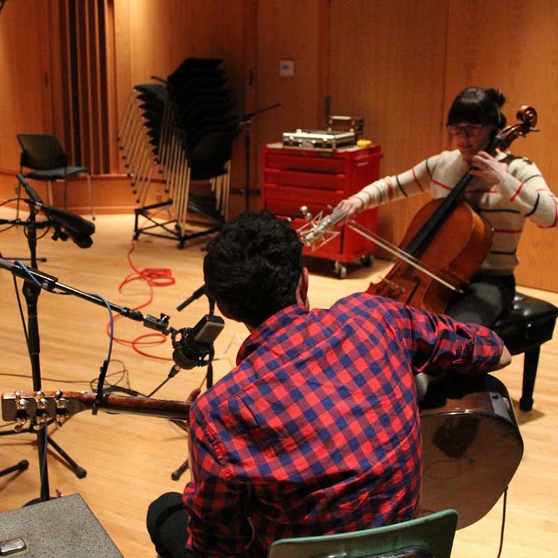 A female and male student playing instruments in the studio and recording music.
