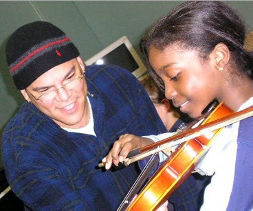 Man in winter hat teaching young girl the violin.