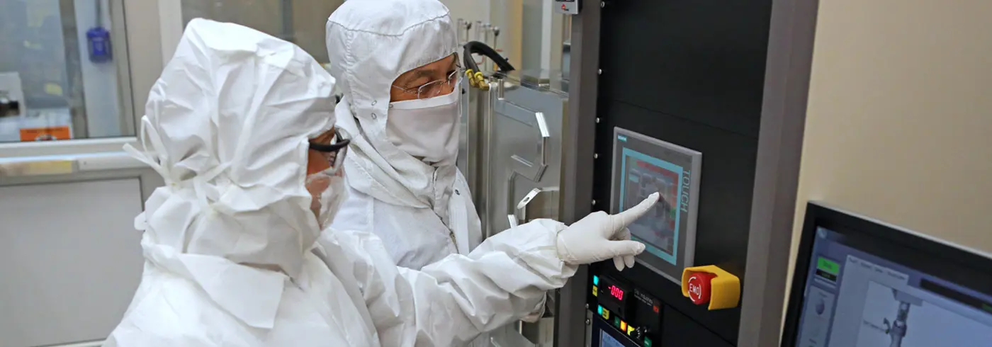 Two lab workers using a screen display on a piece of lab equipment in the Nanomanufacturing lab.
