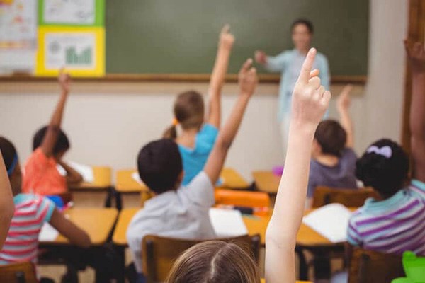 Kids raising their hands in classroom