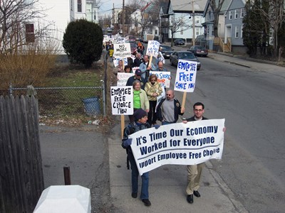 Workers carry signs and banners that say "it's time our economy worked for everyone"