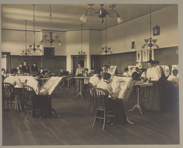 At the turn of the 20th century, Lowell Normal School students used the north light of the large drawing room on the third floor of Coburn Hall to sketch during a drawing class. The adjustable desktops served as easels during art classes.
