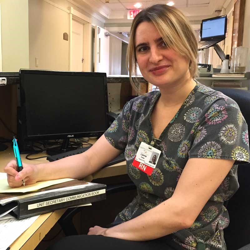 UMass Lowell graduate Lianna Partee taking notes at a desk working as an RN at a hospital