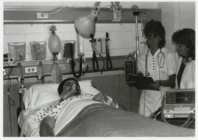 Two nursing students look over a "patient" in a nursing intensive care unit lab in 1989