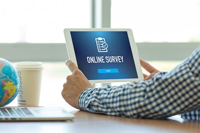 Man's hands holding screen with Online Survey on it