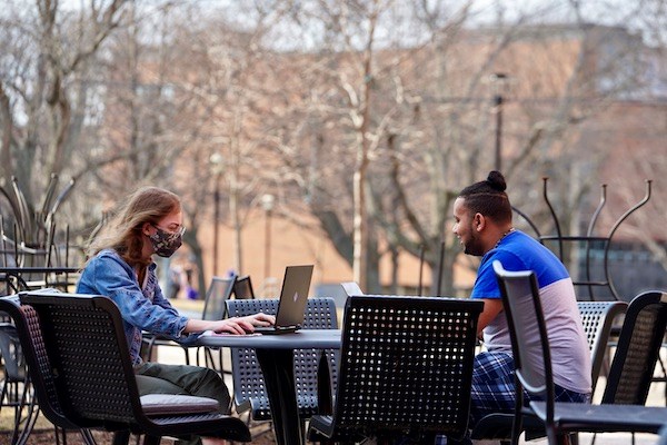 two students sit at a table outside University Suites