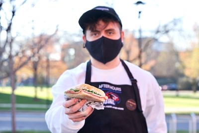 Alec Itzaina holds a panini sandwich 