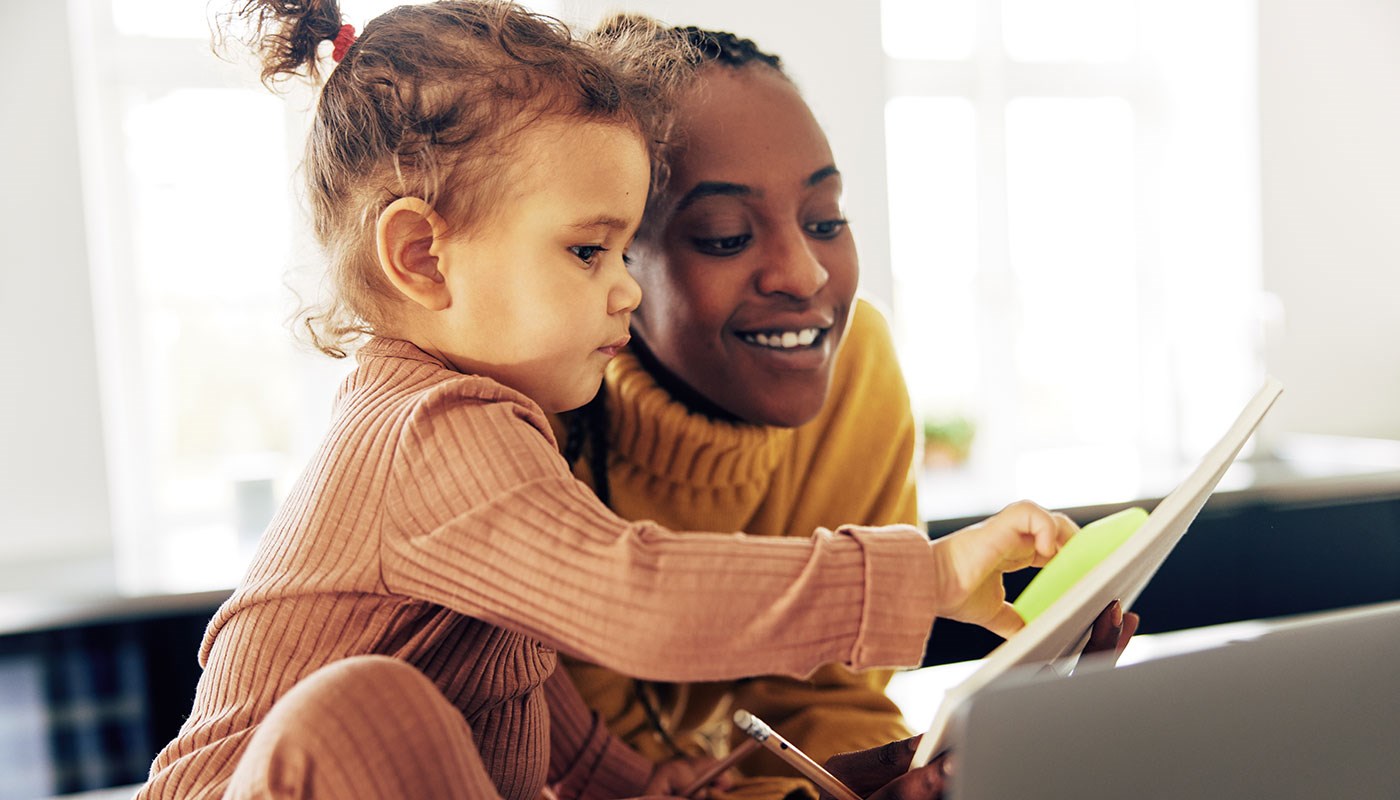 Woman looking at laptop screen with little girl