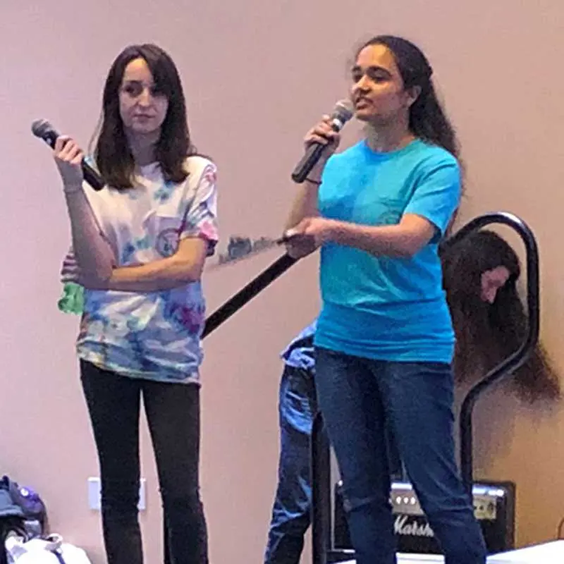 Two students on stage and holding microphones.