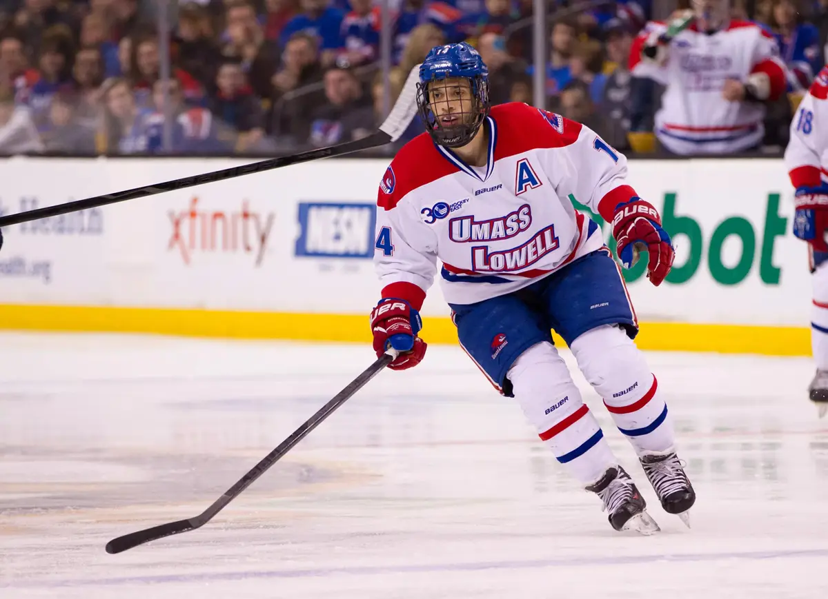 A college hockey player skates on the ice.