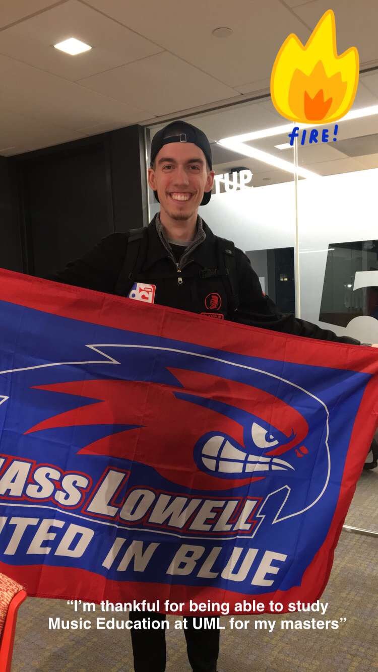 Student holding UMass Lowell flag is "thankful for being able to study Music Education at UML for my masters"