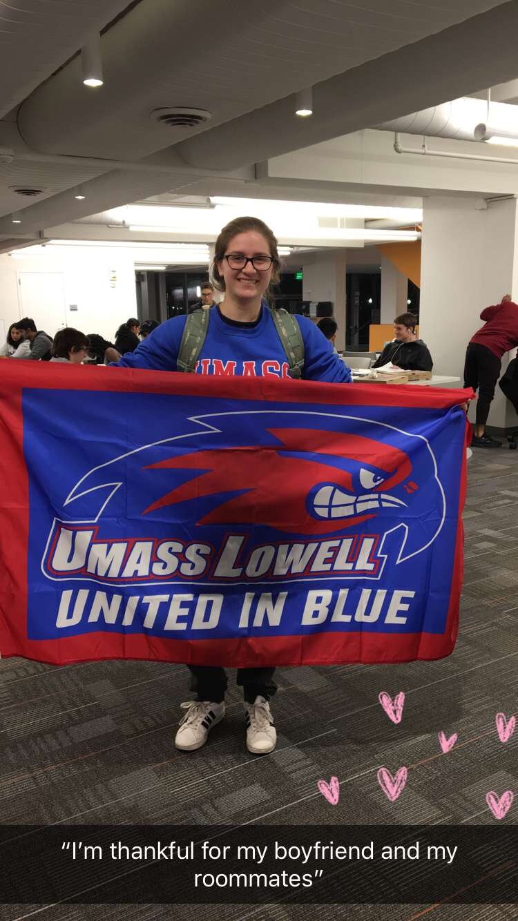 UMass Lowell student holding Riverhawks flag is thankful for her boyfriend and her roommates