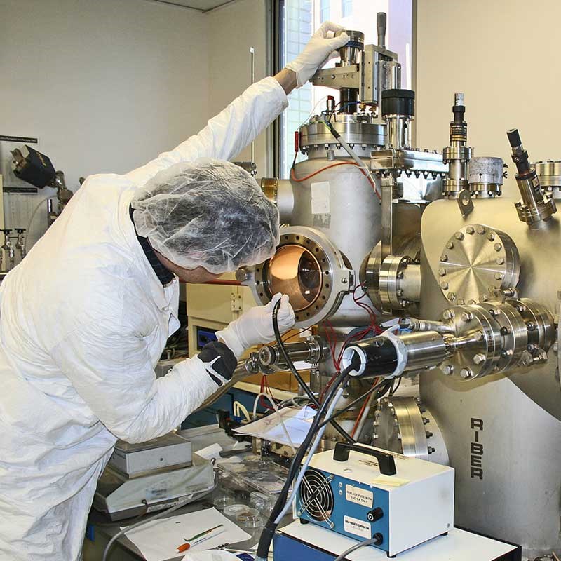 A UMass Lowell physics student works with a large piece of lab equipment