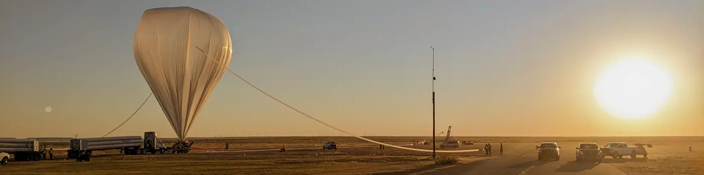 Image of a large NASA balloon being inflated at sunrise.