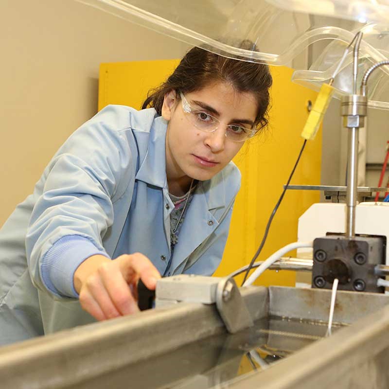 A plastics engineering student works with machinery in a plastics recycling lab at UMass Lowell