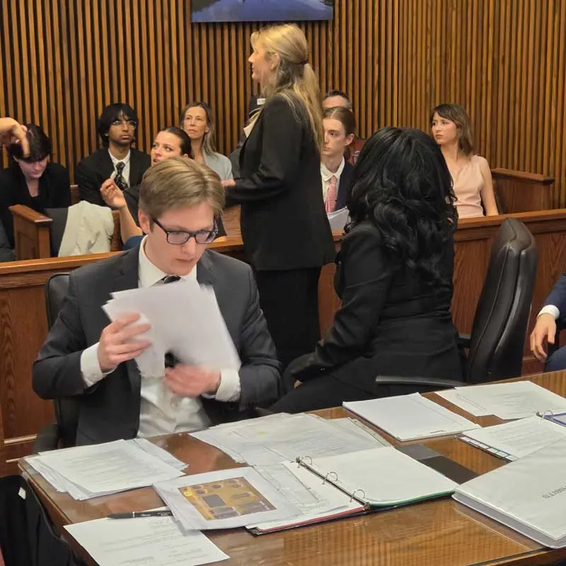 Students from UMass Lowell's Mock Trial team prepare to start a trial in a court room.