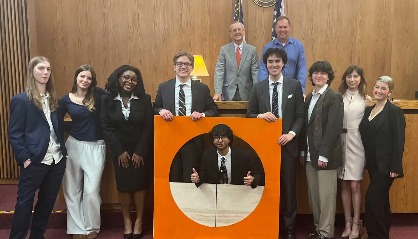 Students from UMass Lowell's Mock Trial team pose in a court room.