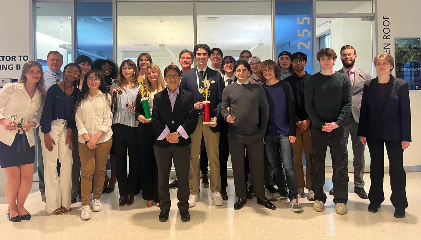 UMass Lowell Mock Trial students hold trophies while posing with Chancellor Julie Chen.