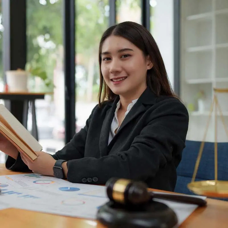 Student holds a book while seated at a desk with a judicial gavel nearby.
