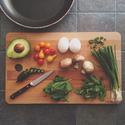  Purchasing-Food and Beverages: a wooden cutting board with vegetables and fruits on top of it, as well as a knife ready to cut them to make them into a dish.