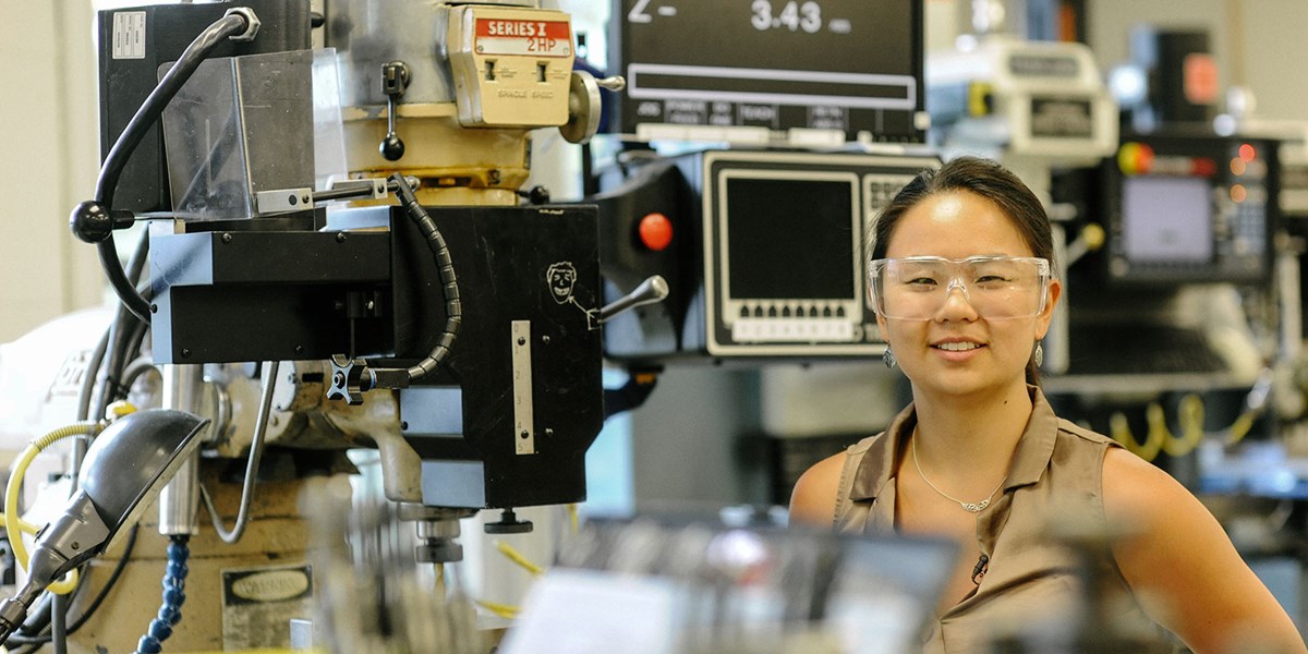 Mechanical Engineering major Qiana Curcuru standing in front of equipment at iRobot, where she co-oped.