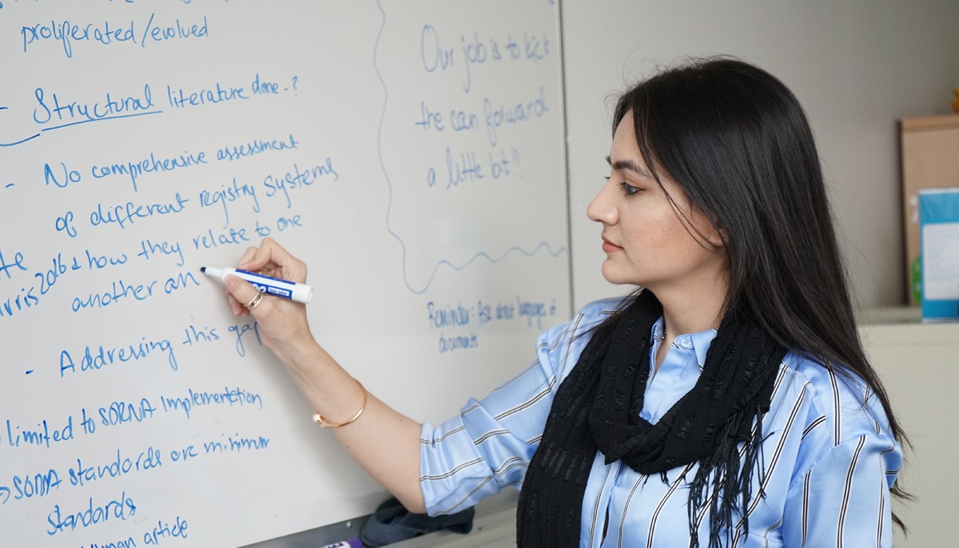 Qurat Ann writes on a whiteboard with a blue marker