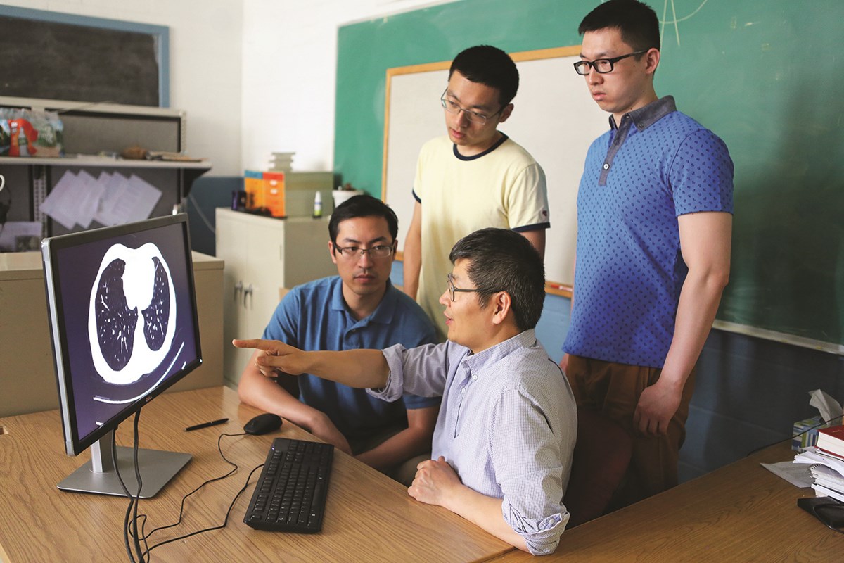four researchers looking at computer screen