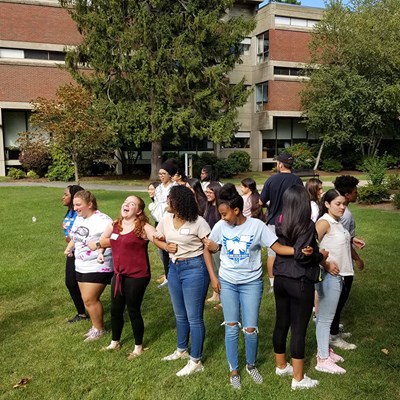 Students standing in circle with interlocked arms outside
