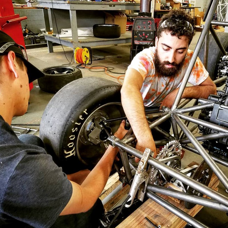 Two students from UML’s Society of Automotive Engineers work on building a Formula One racecar
