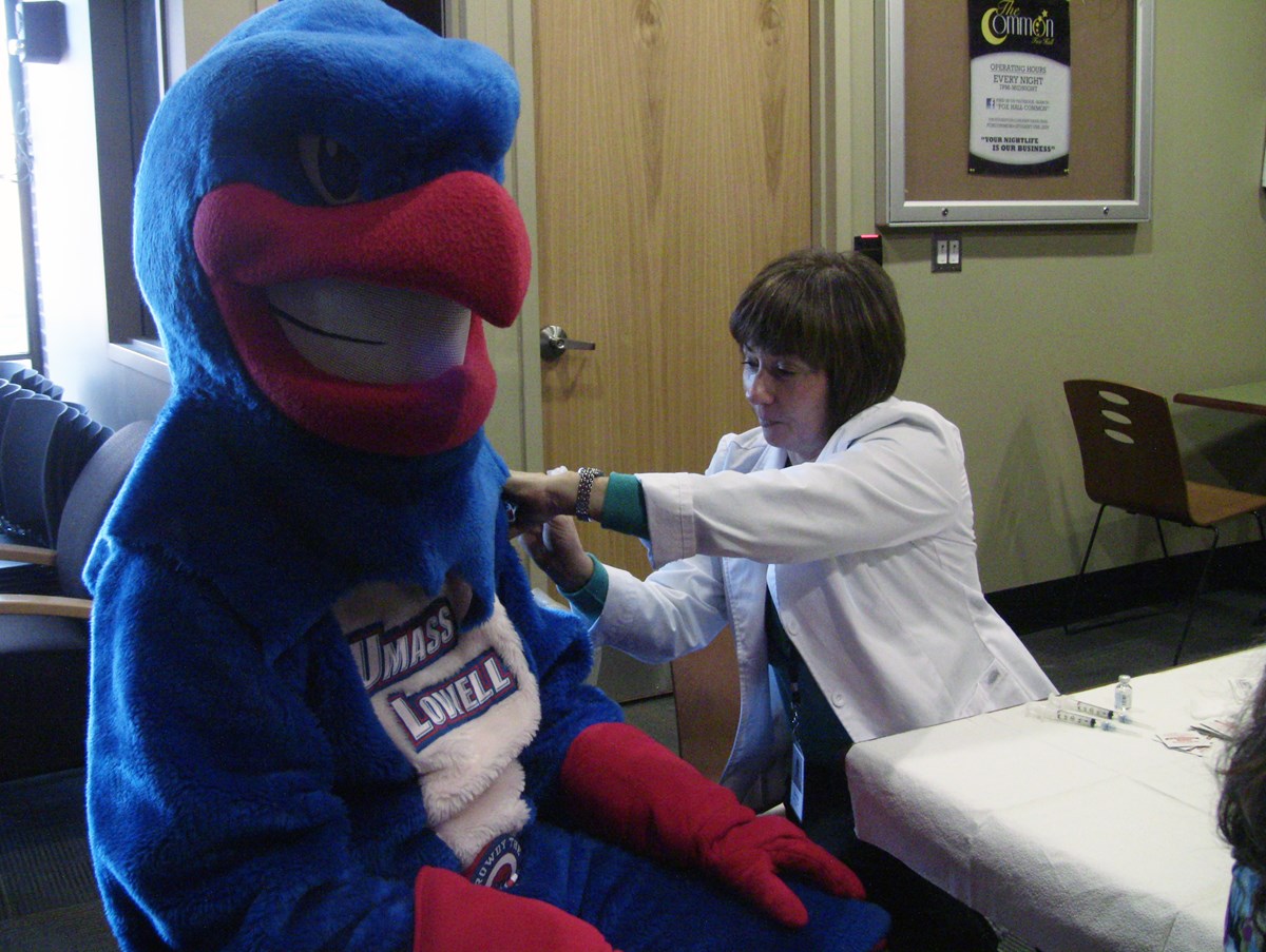 UMass Lowell Mascot Rowdy the River Hawk getting a flu shot from a nurse.