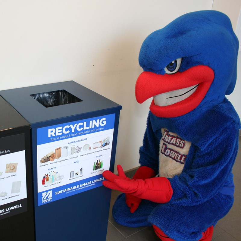 Rowdy the River Hawk pictured next to one of UML's many recycling bins