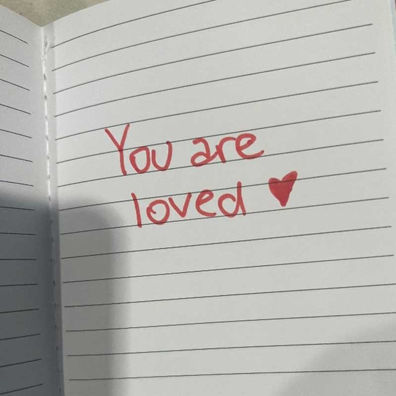 Open journal page with the words written "You are loved"