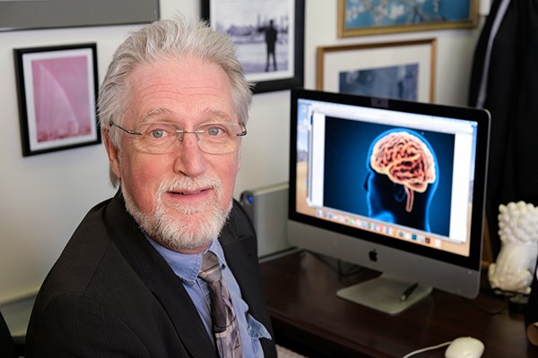 Prof. Thomas Shea in front of computer with brain on screen