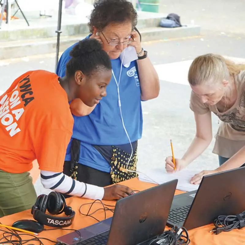 A student and two adults work at a table for a YWCA event
