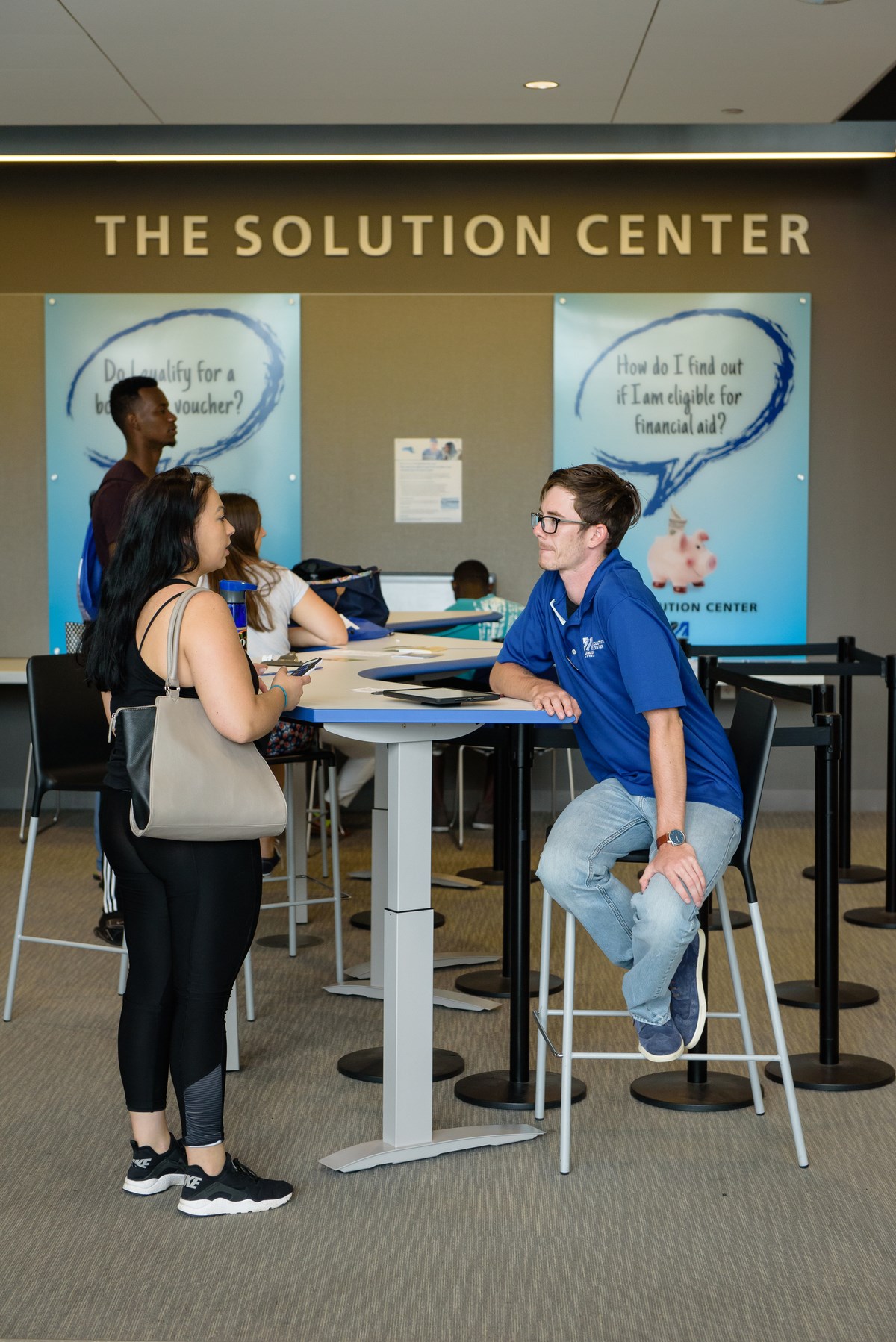 Female and male student talk at high-top table at solution center