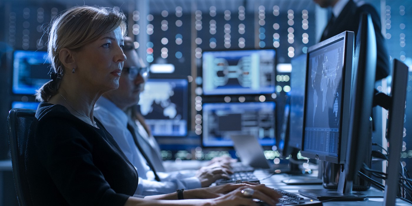 Stock image: Female Government Employee Works in a Monitoring Room. In The Background Supervisor Holds Briefing. Possibly Government Agency Conducts Investigation.