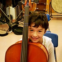 A child from the String Project poses backstage with his cello before the concert.