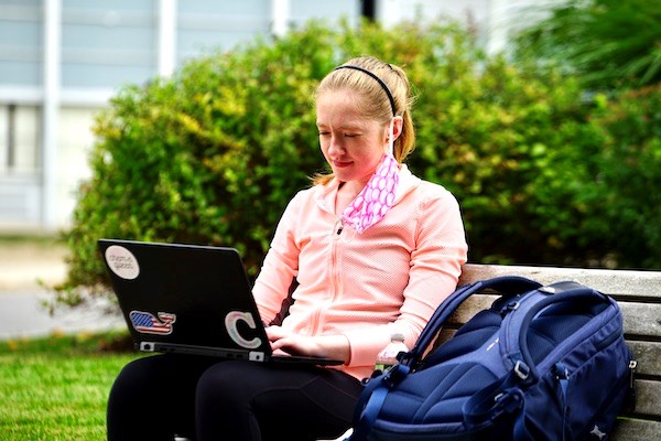 A student works on her laptop sitting on a bench