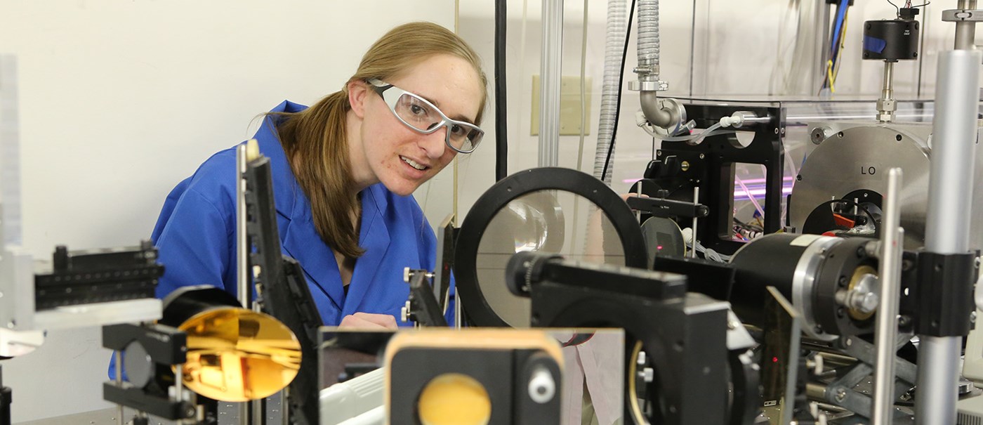 A female Biomedical student inspecting a machine in a lab.