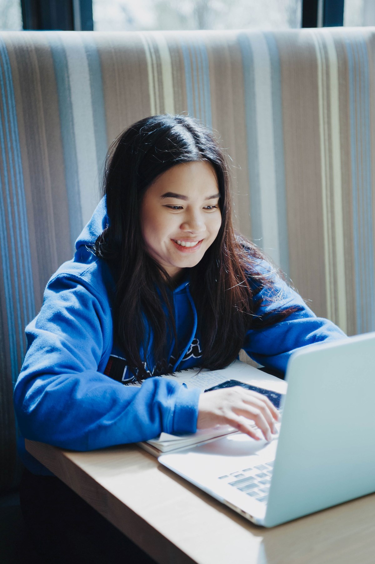 A female student types on a laptop smiling.