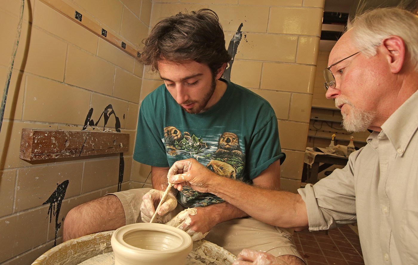  A student and professor work on a pottery wheel.