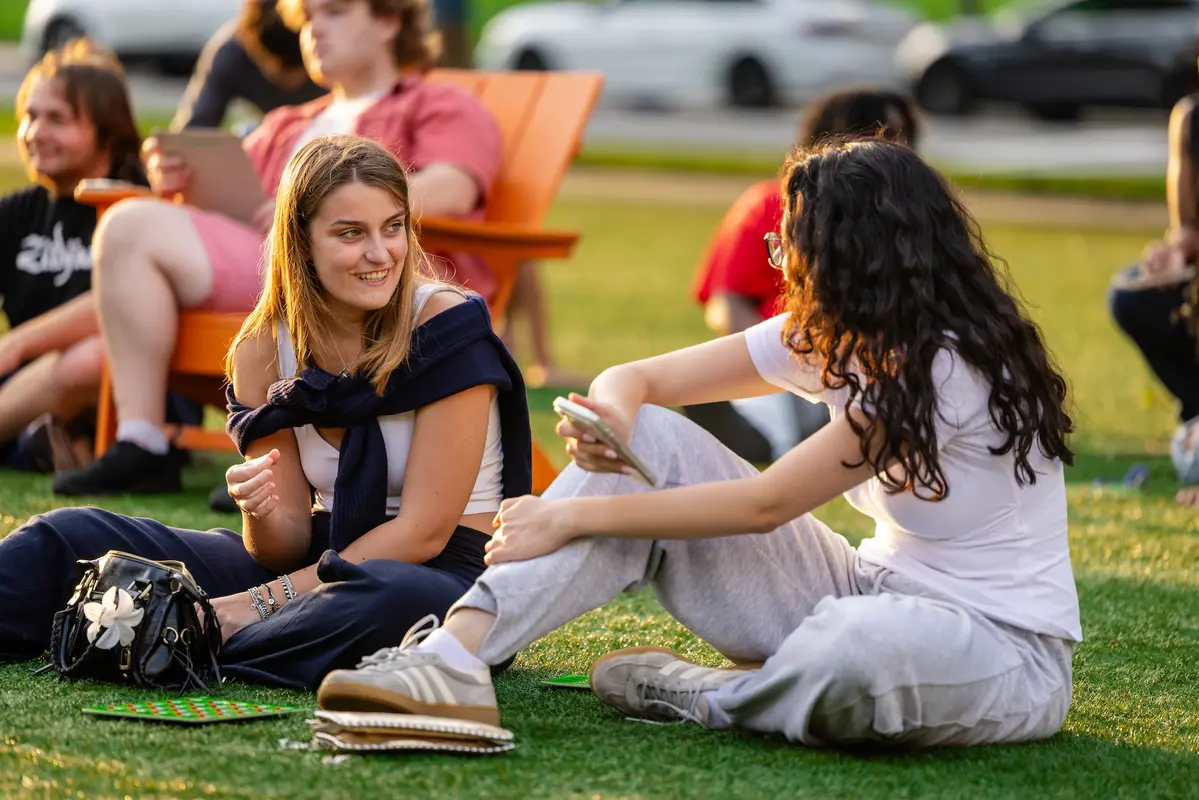 Two students sit on the campus green enjoying the Engagement Fair.
