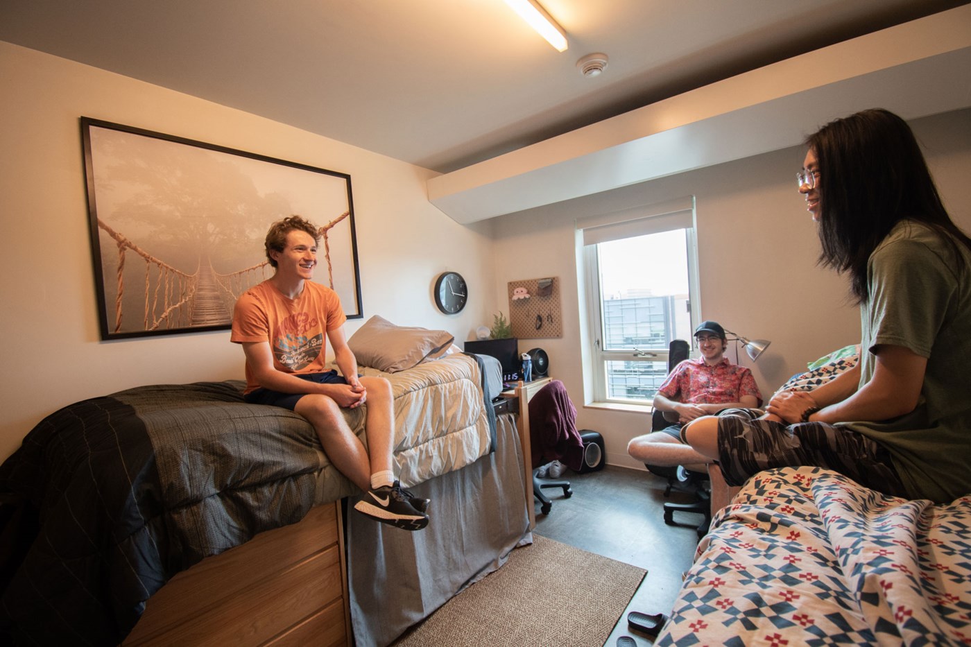 Three students sitting around residence hall room