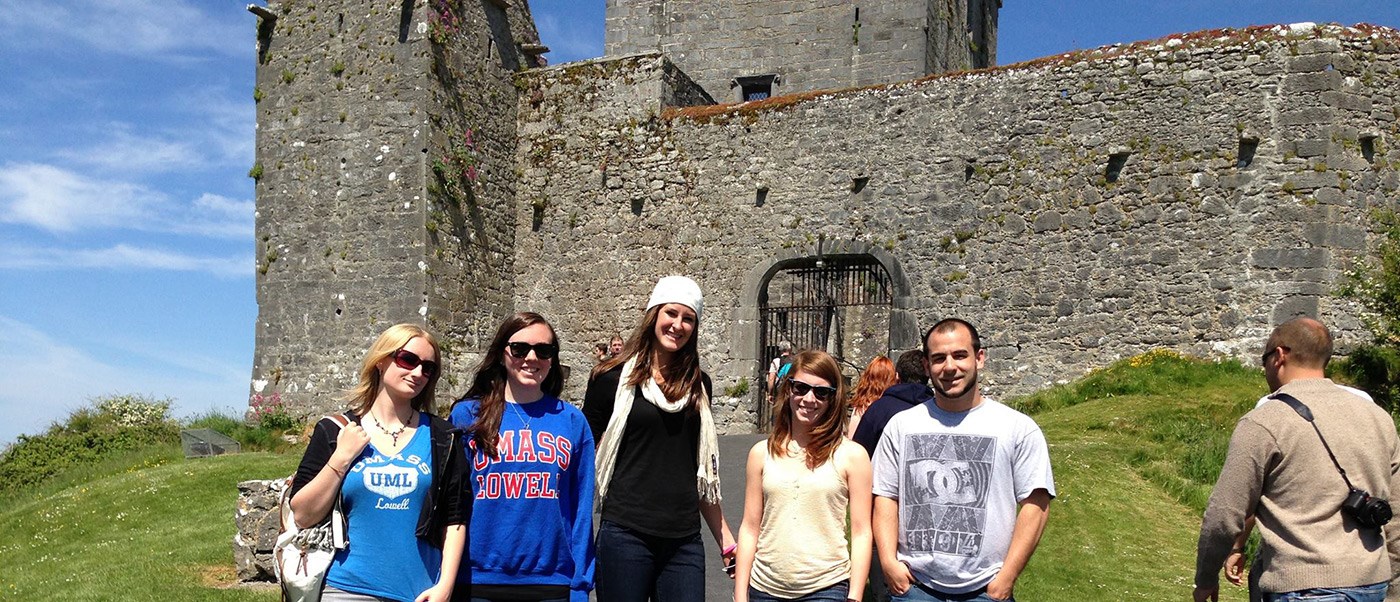 A group UMass Lowell Study Abroad students pose for a photo in front of an Irish castle.