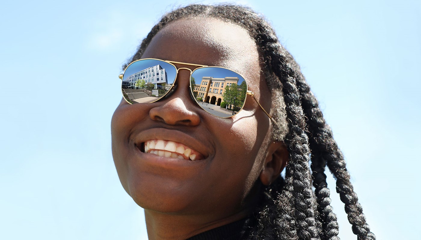 Benedicta Agyemang-Brantuo smiles wearing sunglasses that reflect UMass Lowell buildings in them.