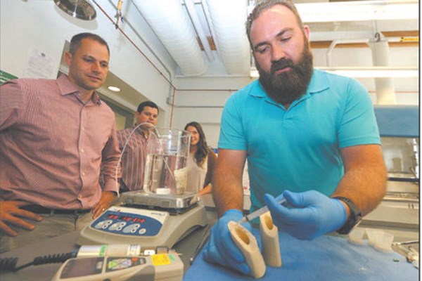 Brian Hess, Andrey Marchenko and Christy Cavaleri watch Mike Brown apply the glue to a piece of bone. 