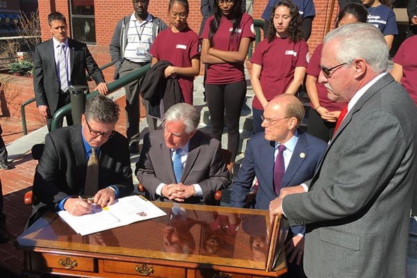 From left, Worcester State University President Barry Maloney signs the Commonwealth Commitment on the steps of Middlesex Community College in downtown Lowell Thursday morning as UMass President Marty Meehan, MCC President James Mabry and Higher Education Commissioner Carlos Santiago look on.